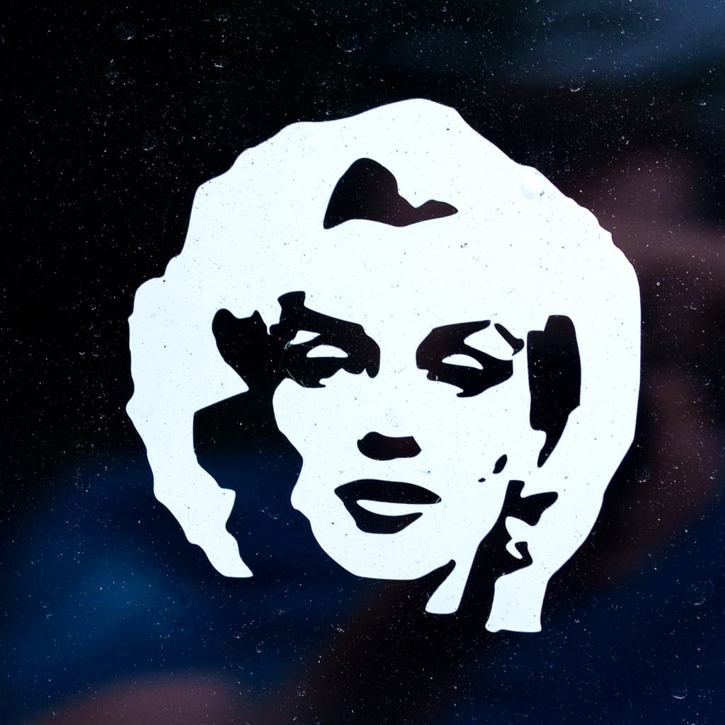 A white vinyl decal of a woman's face applied to a dark window